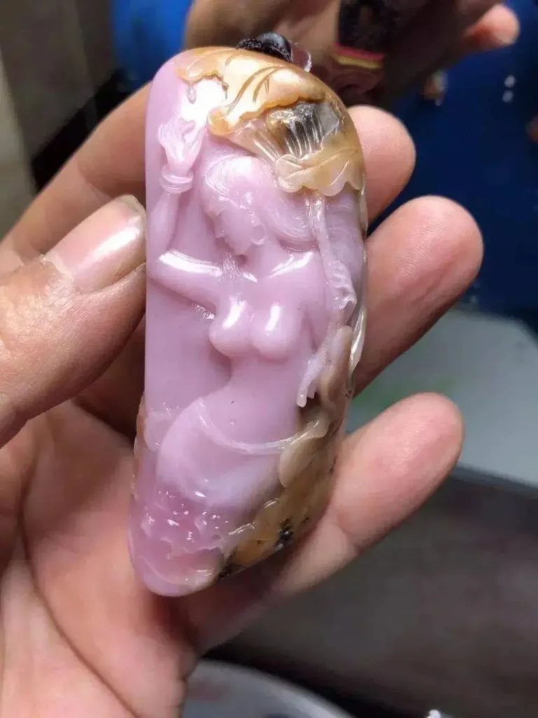 A small pink stone carving showing delicate details and a soft lavender-pink luster.