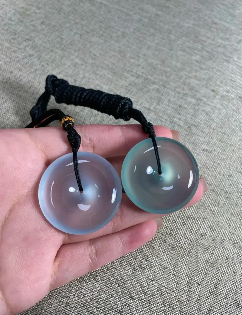 Two high-translucency blue and teal jadeite Ping'an Kou pendants with deep vitreous luster.