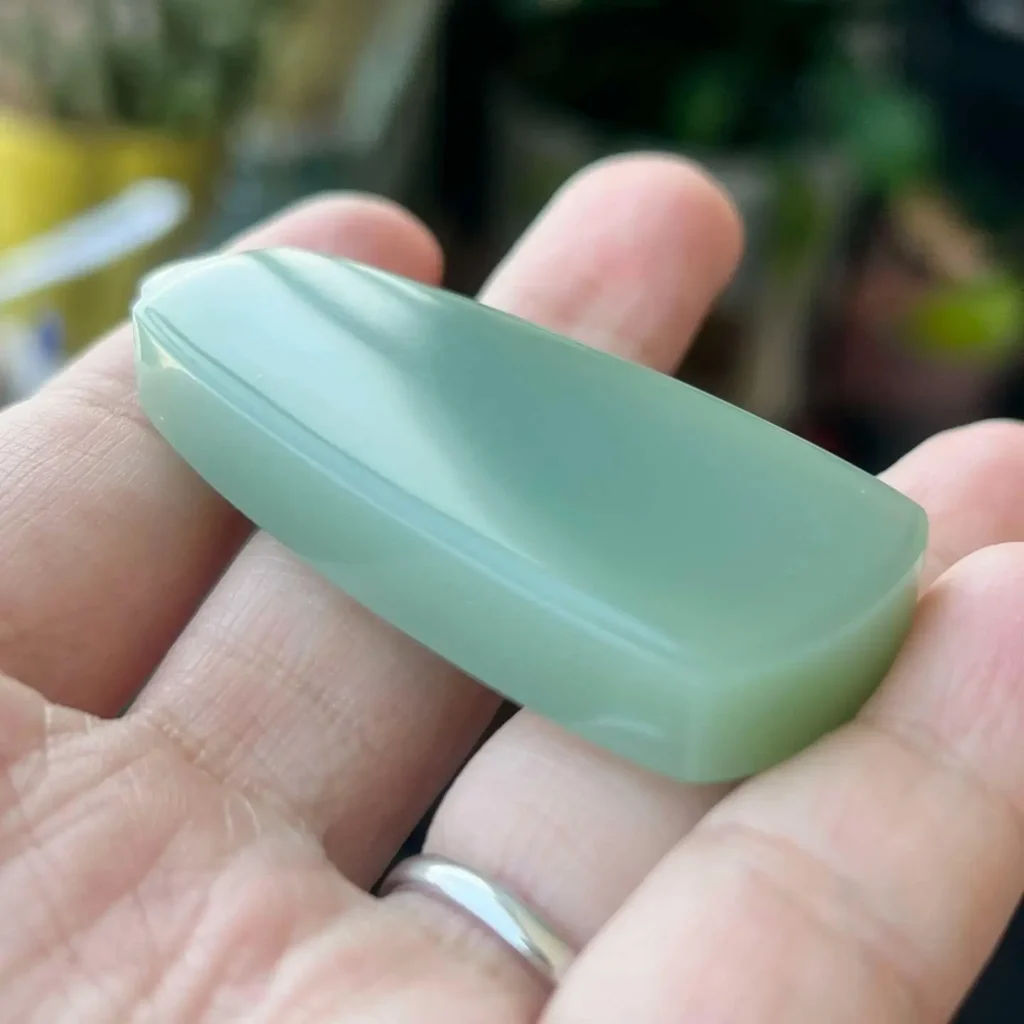 Greenish-gray Hetian jade pendant showing a soft, diffused greasy luster on its dense surface.