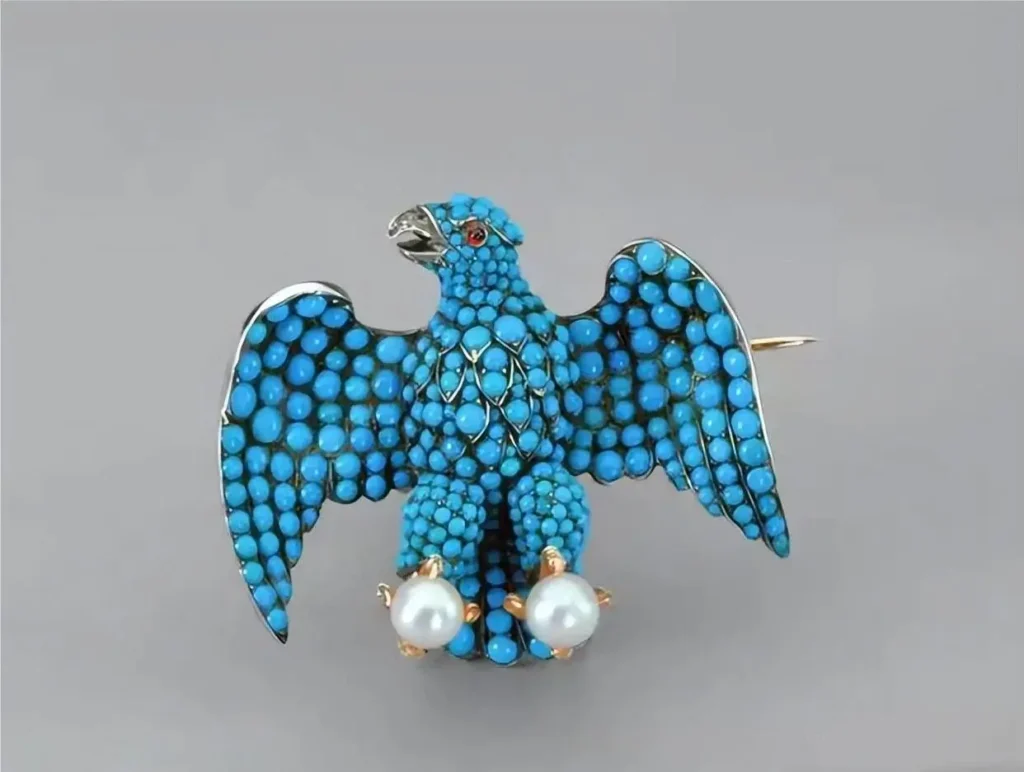 An eagle-shaped brooch in gold, fully set with a dense pavé of small turquoise gemstones.