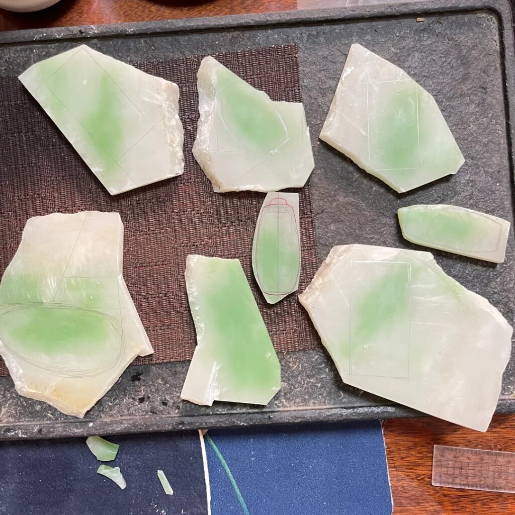 Raw nephrite stone with vibrant green chromium infusion on a white base.
