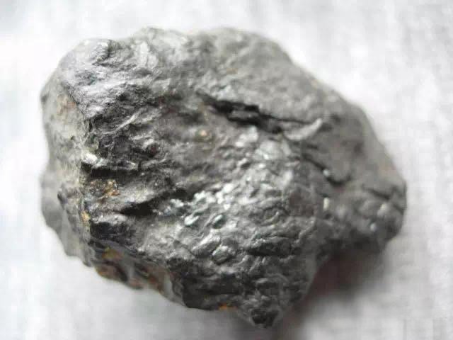 A raw Fushun amber specimen with dark coal inclusions, a unique find among the Gemstones of Liaoning.