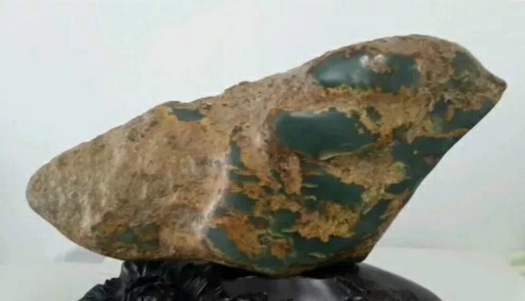 Raw Hemojade stone featuring a thick outer skin and distinct, unrounded edges.