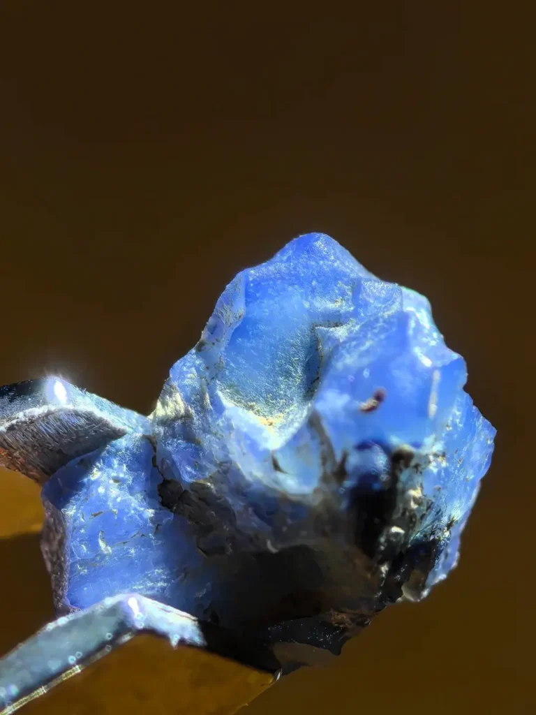 A raw blue sapphire grain from Penglai, Hainan, showing irregular shape and vitreous luster.