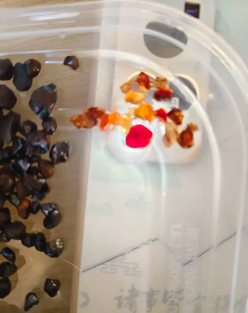 A small, vibrant red zircon crystal found on-site in Penglai, Hainan, showcasing natural color.