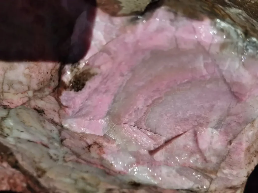 Raw specimen of Sichuan Rhodonite showcasing vivid peach-red hues and crystalline structure.