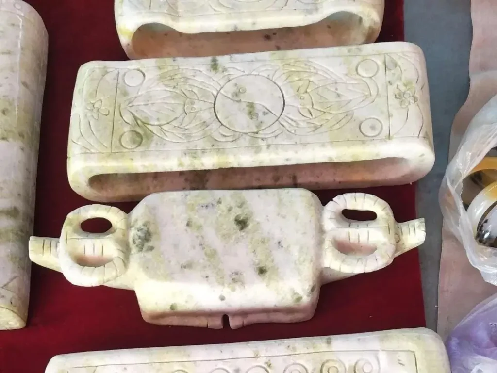 Diverse Shaanxi Lantian Jade carvings showing waxy luster and colors from pale green to greyish-white.