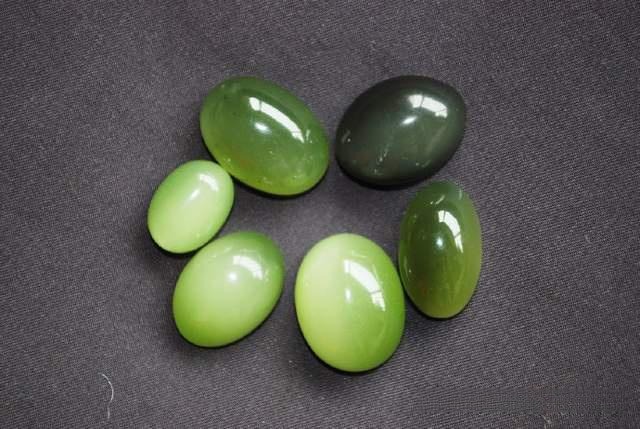 A collection of Sichuan nephrite cat's eye gems in green, honey yellow, and misty gray hues.