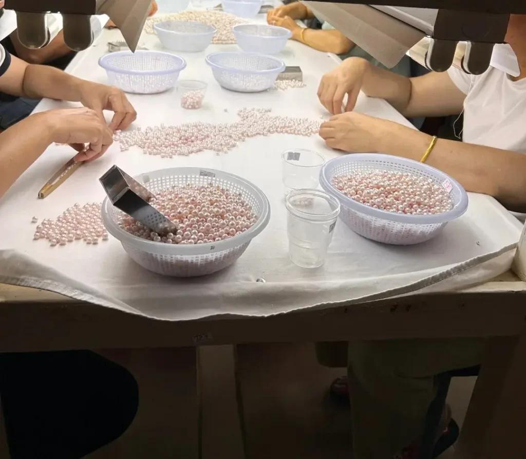 Leizhou workers sorting lustrous Southern Pearls under focused lighting in a Guangdong pearl farm.