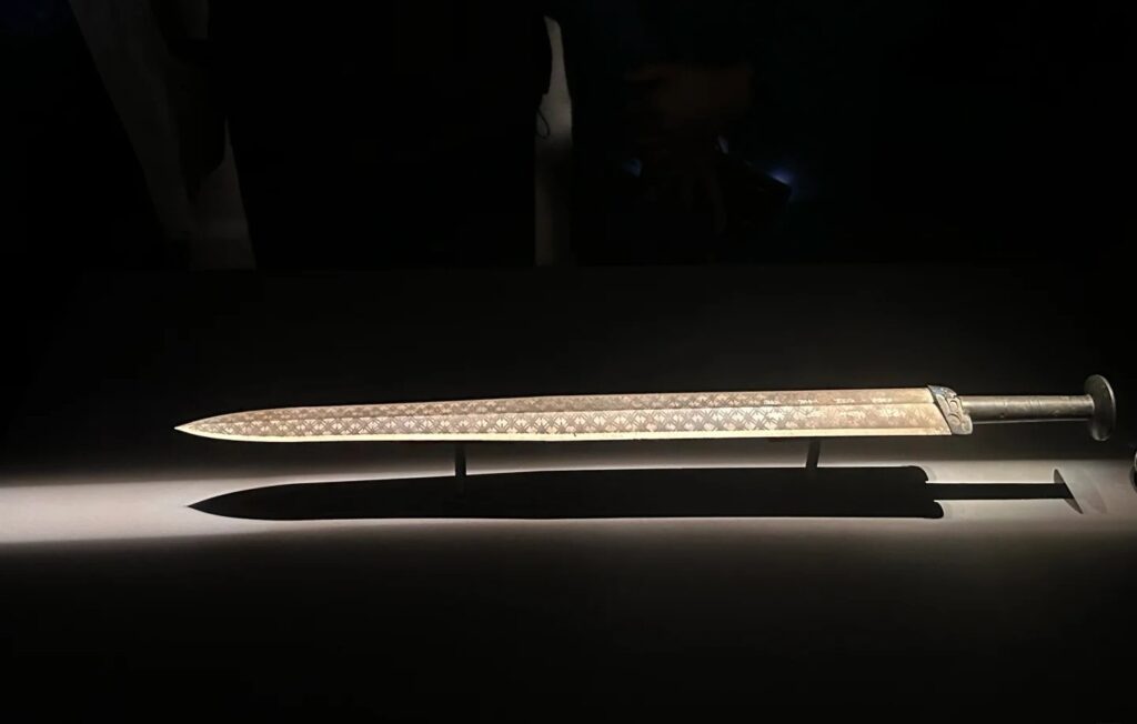 The Sword of Goujian displayed in a museum, featuring a bronze blade and turquoise-inlaid hilt.