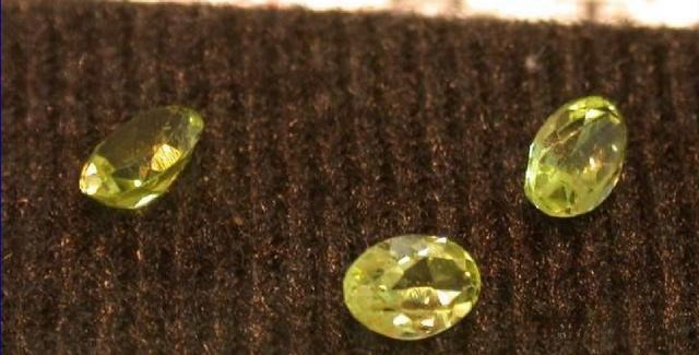 Three faceted Jilin peridot gemstones showing a characteristic pale yellow-green hue.