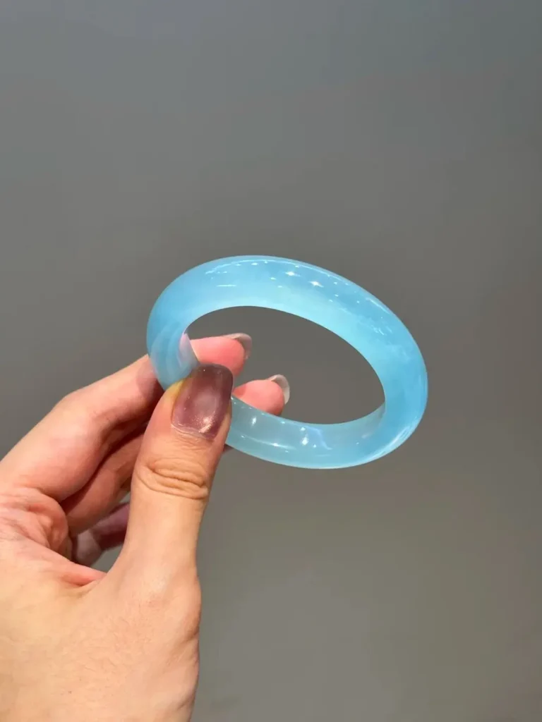 A high-translucency blue serpentine jade bangle from Xinjiang showing a soft blue-green hue.
