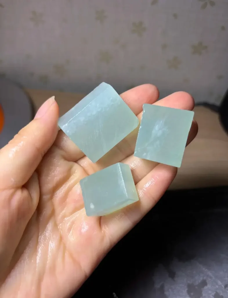 Three polished slabs of blue Tianqingdong raw material held in a palm to show scale and volume.