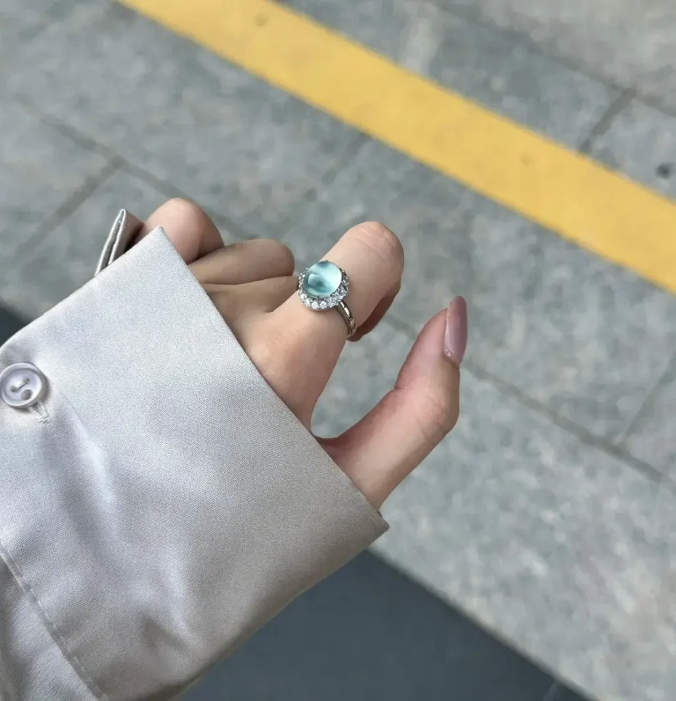 A blue Tianqingdong serpentine cabochon ring worn on a finger under bright natural sunlight.