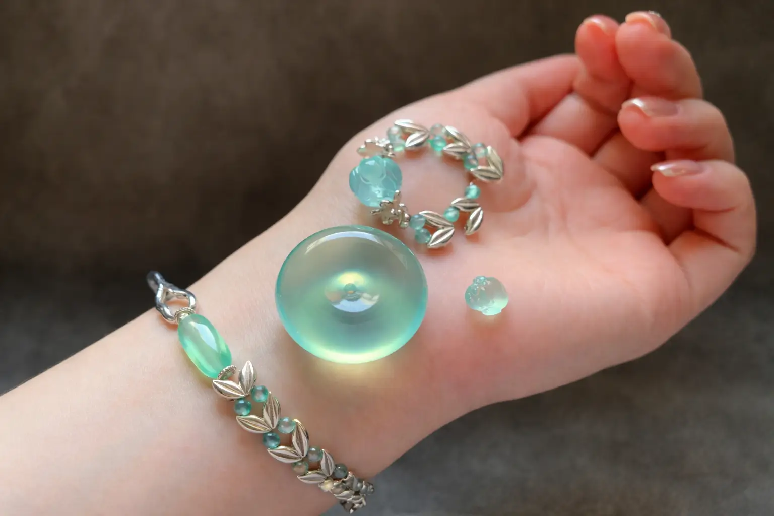 A side-by-side display of blue serpentine and jadeite jewelry on a wrist with matching clarity.