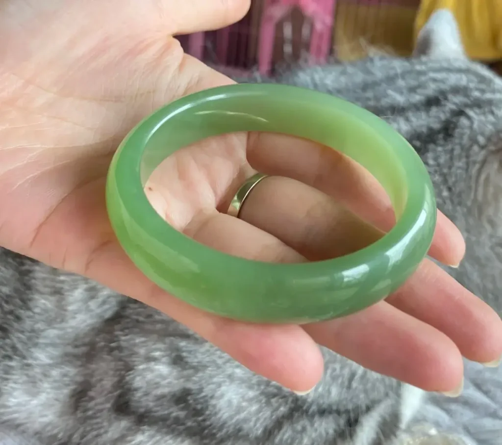 Russian Cui Qing Nephrite bangle with a vivid green band on a stark white base.