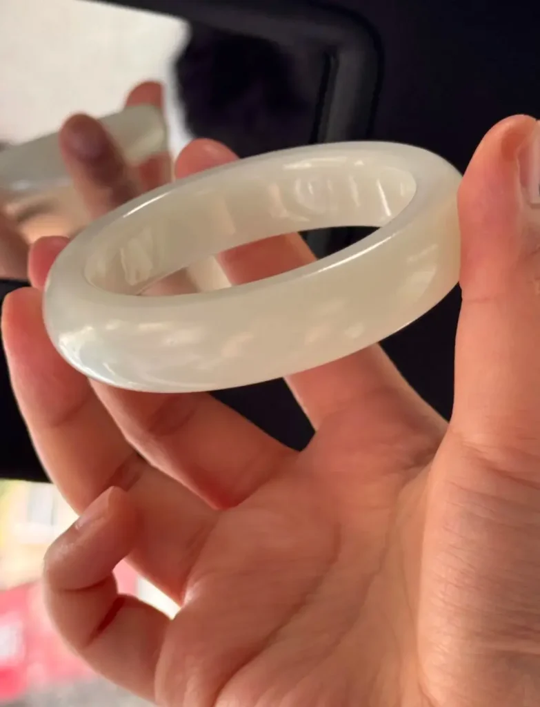 White Hetian jade bangle showing a soft, diffused greasy luster and microcrystalline structure.