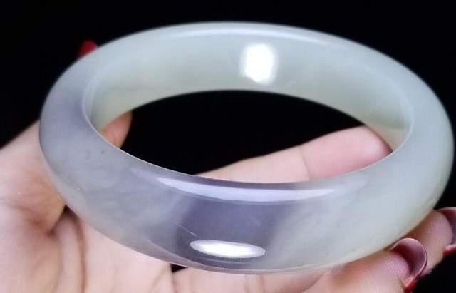 White Qinghai nephrite bangle with a single fluid drift of grey-violet and uniform fine structure.