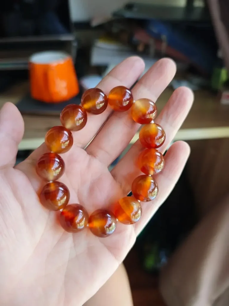 Xunke agate bead bracelet in palm, showing high transparency and vivid scarlet red.