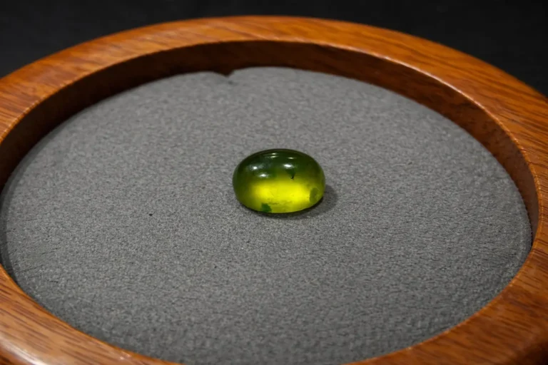 A yellow-green Vesuvianite Jade cabochon with a brilliant, glass-like vitreous luster.