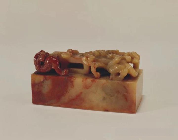 A Shoushan stone seal with two carved hornless dragons on top and Chinese characters on the base.