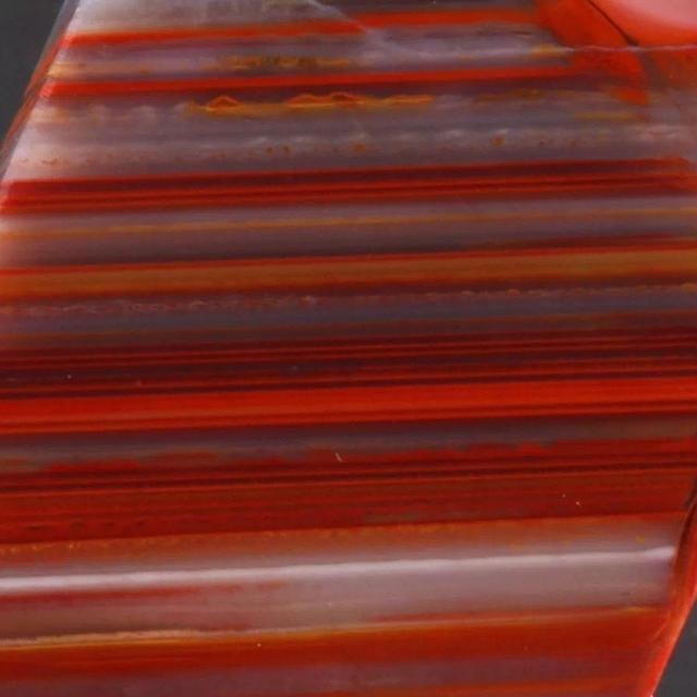 Macro view of Zhan-Guo Red agate with layered silk-like bands and subtle black stripes.