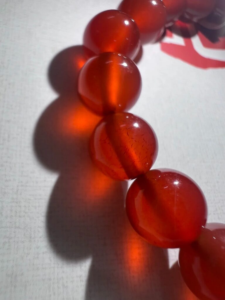 Close-up of dyed red agate showing artificial color concentration in cracks and surface fissures.