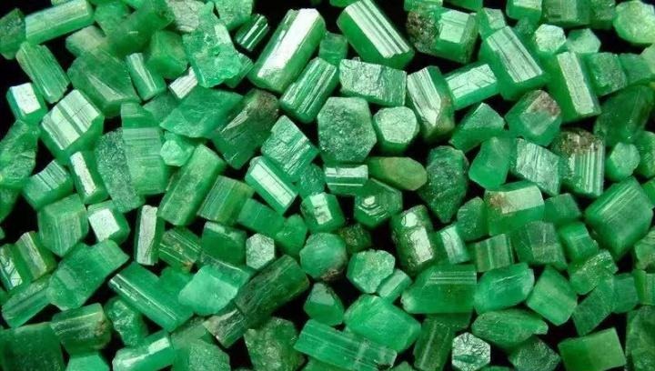 A collection of rough green emerald crystals from Malipo showcasing hexagonal prismatic structures.