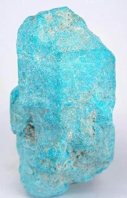 A raw, light blue turquoise specimen with a porous texture, showing apatite pseudomorph structure.