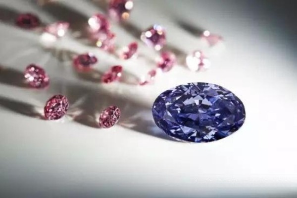 An oval purple diamond sits in the foreground with smaller pink diamonds scattered behind it.