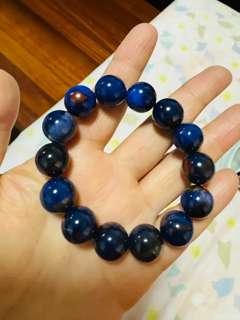 A blue-purple gemstone round bead bracelet featuring distinct globe-like natural matrix patterns on a hand.