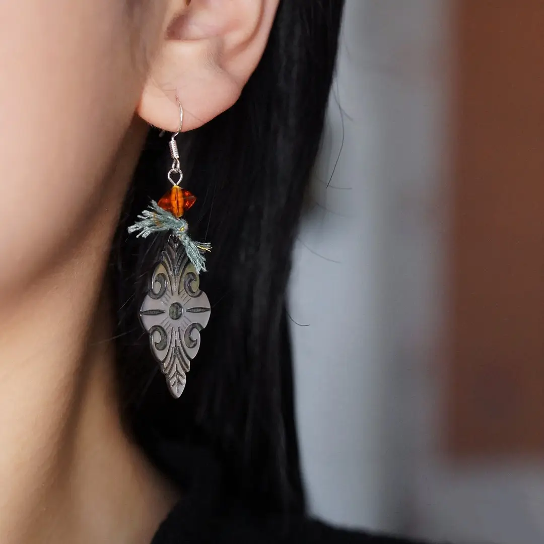 Carved MOP earring hanging on a woman's earlobe, showcasing the 925 silver hook and drop length.