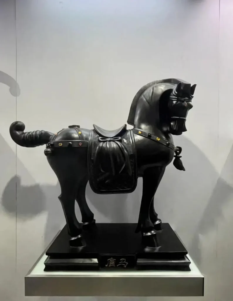 A black jet stone sculpture of a Tang Dynasty style horse with ornate saddle and harness details.