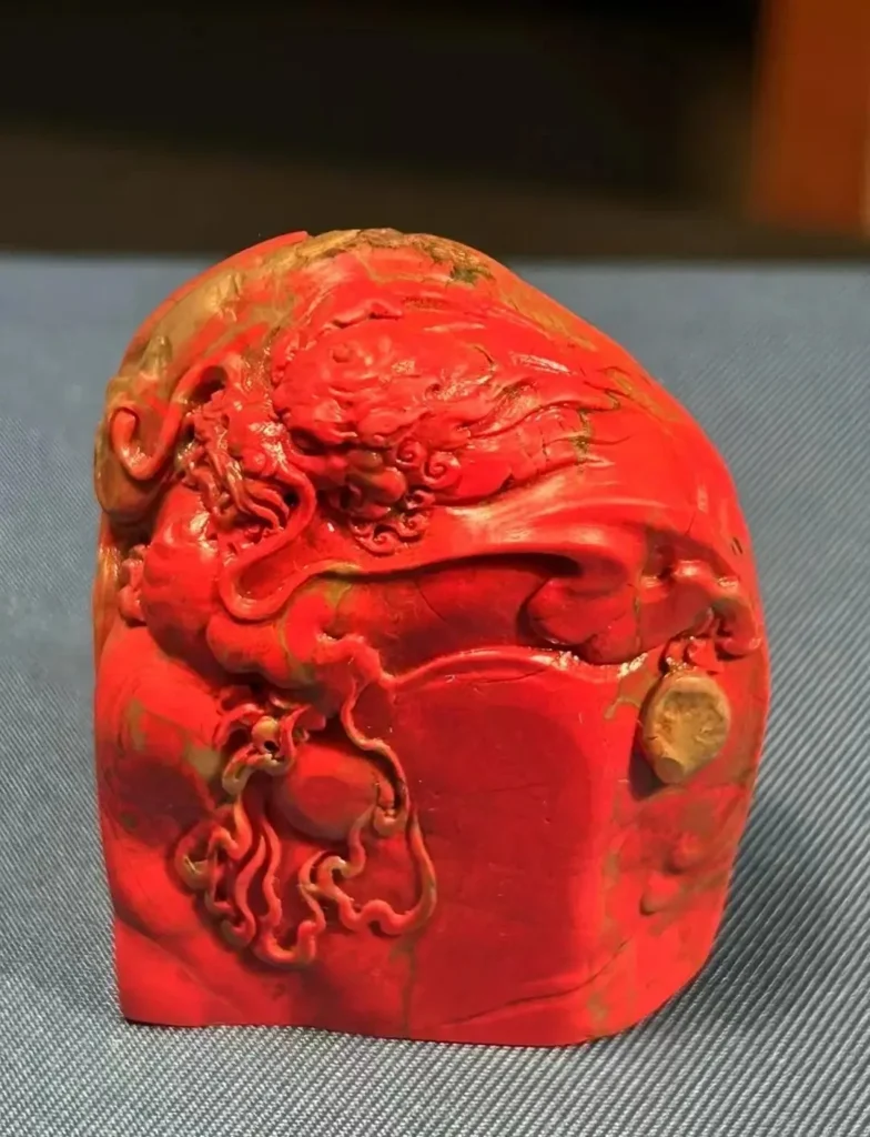 A vibrant red Zhejiang Changhua chicken-blood stone carved with a traditional Chinese dragon motif.