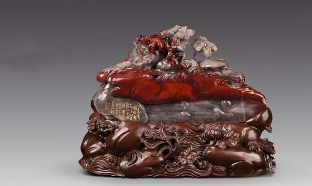 An intricate jade carving featuring flowing red and grey mineral layers with detailed natural motifs.