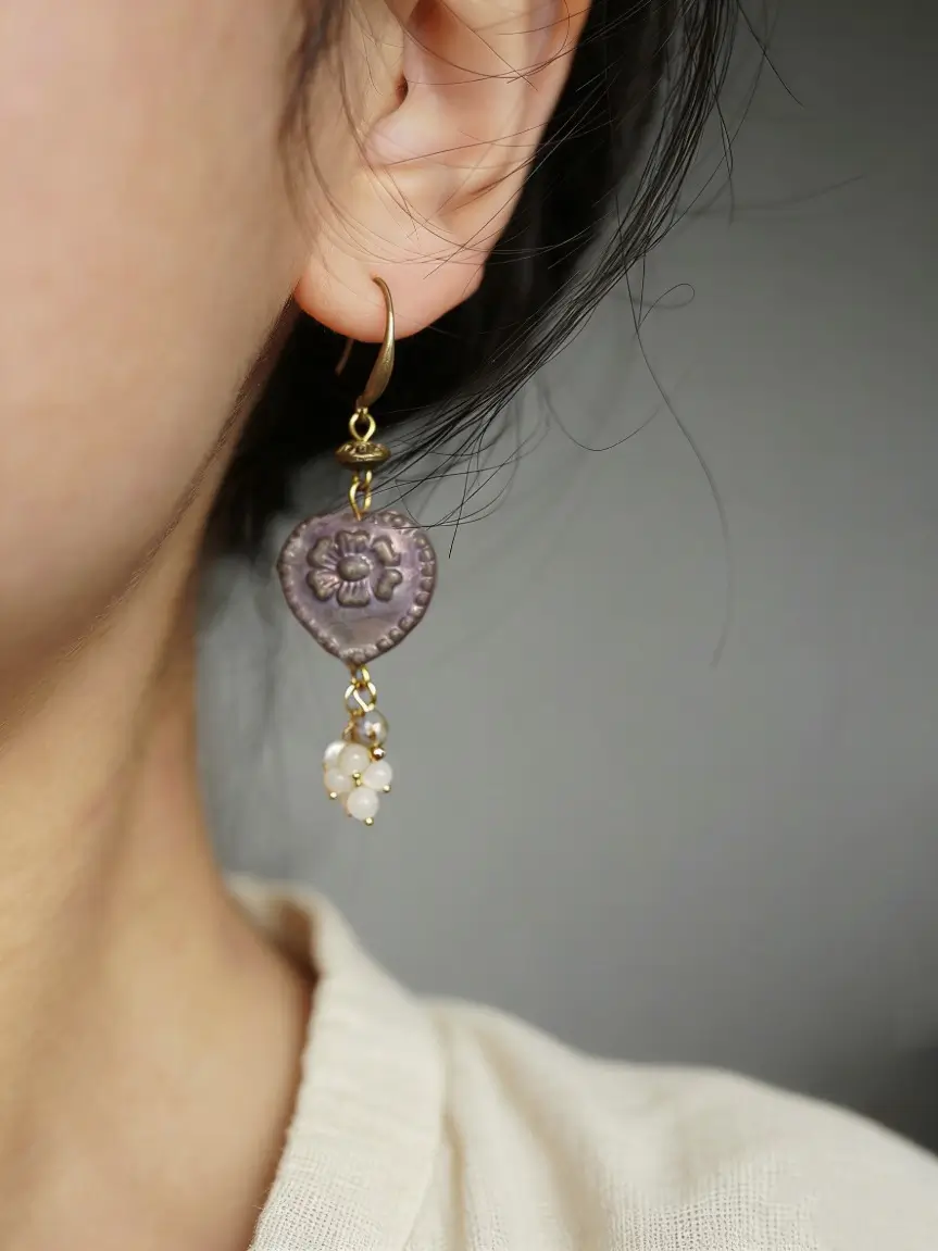 Side profile of a model wearing purple earrings, focusing on the pearl tassels.