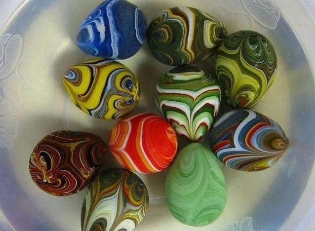 A group of brightly colored glass pebbles with artificial, swirling patterns mimicking Yuhua stones.