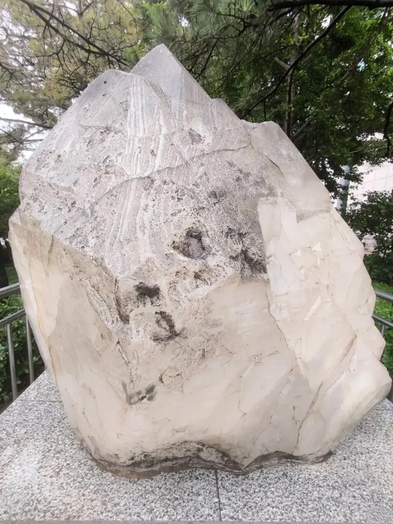 A massive 3.5-ton natural white quartz crystal, standing 1.9 meters tall in a museum plaza.