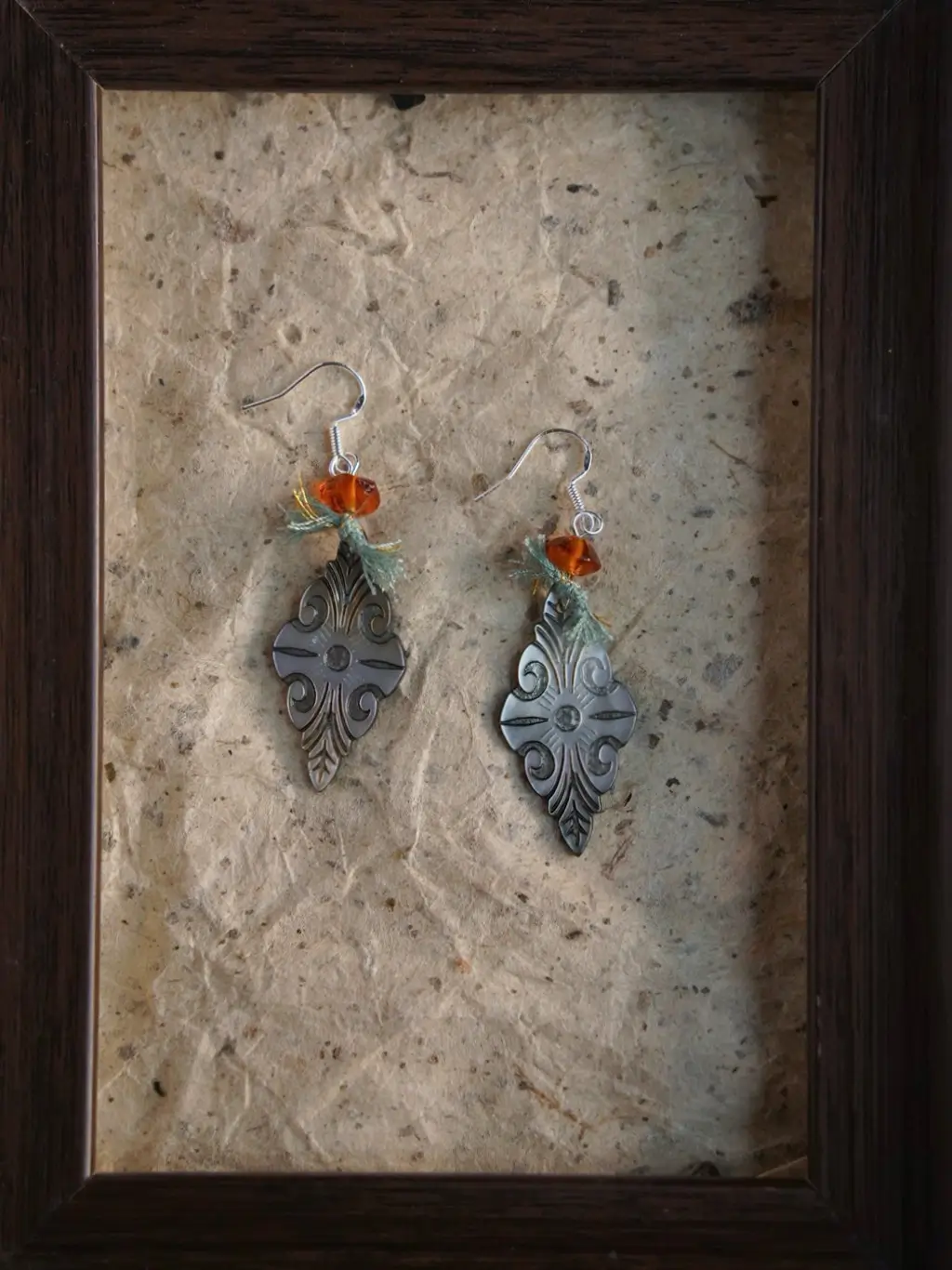 Macro shot of ethnic floral motifs etched on black shell jewelry, resting on vintage aged paper.