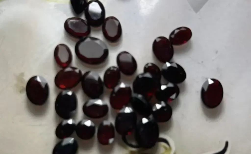 Faceted oval cut red garnet gemstones from Heilongjiang displaying a deep brownish-red hue.