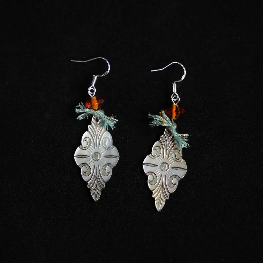 Fanta-orange glass centerpiece on deep vintage purple earrings against a black background.