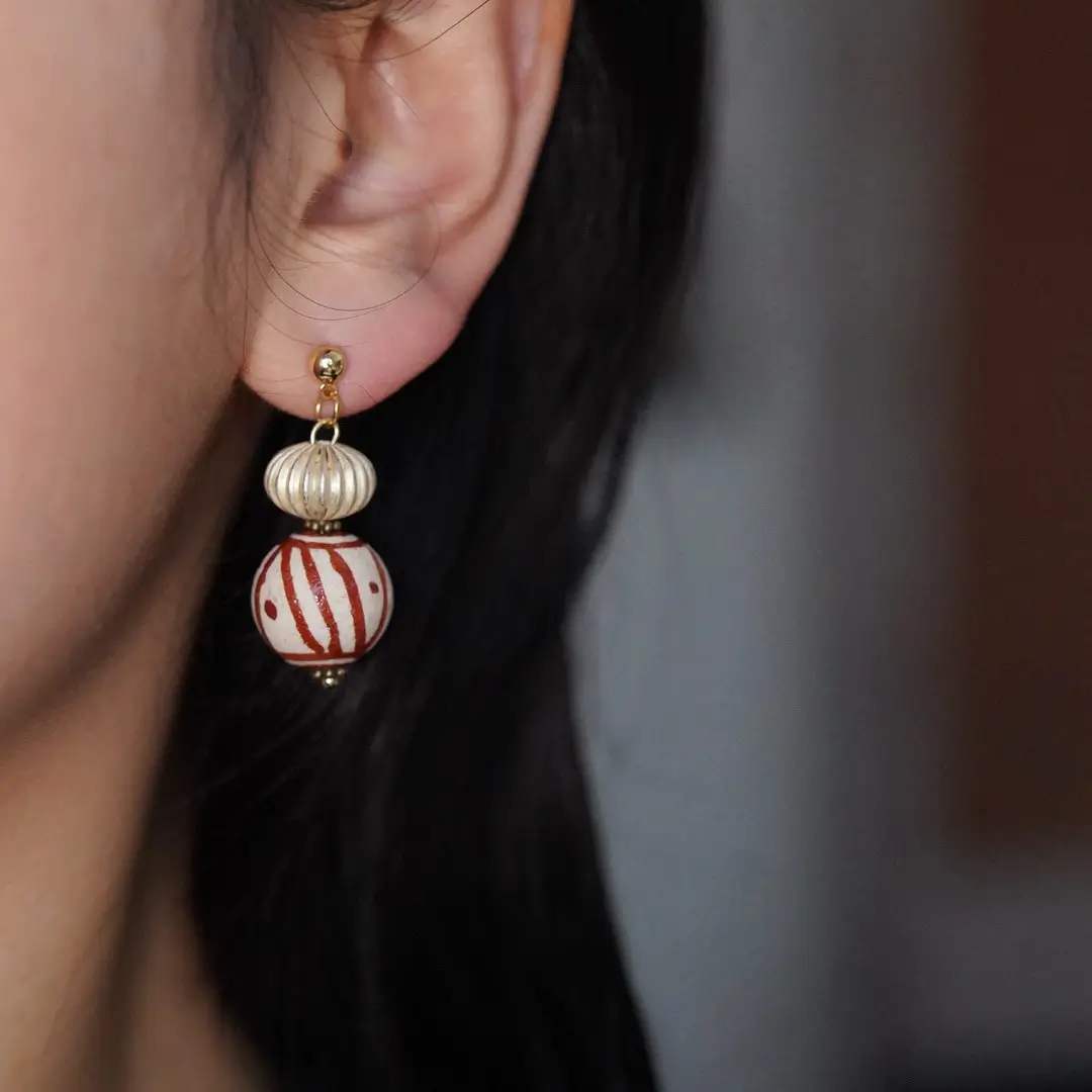 A 925 silver gold-plated earring worn naturally on an earlobe.