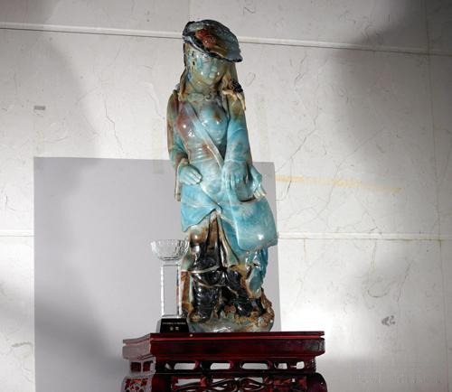 A tall Guicui quartzite woman statue from Guizhou standing next to a gold award trophy.
