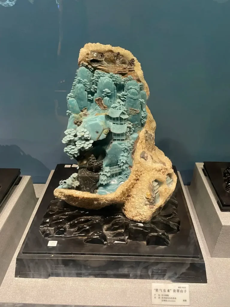 An intricate turquoise Guicui quartzite mountain carving on display at a Guizhou museum.