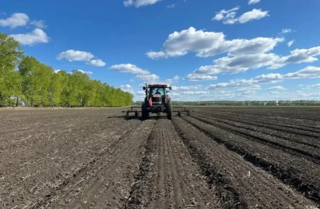 Tractor tilling deep ridges into the dark, rich black soil of Heilongjiang.