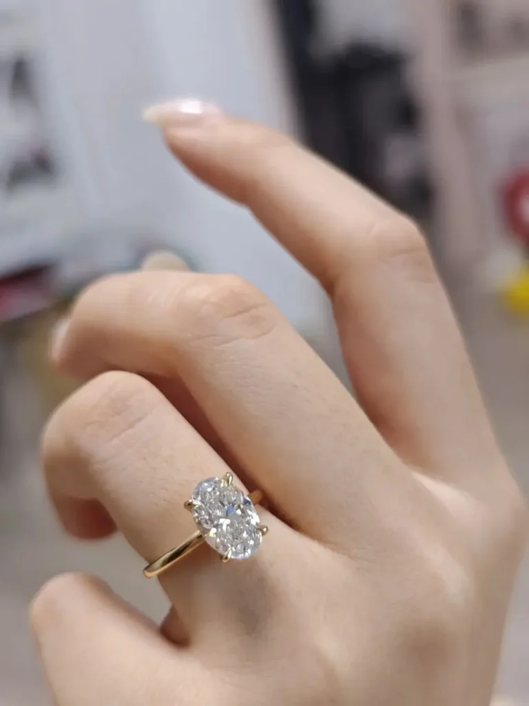 Oval-cut 3-carat Henan lab-grown diamond ring in an 18k gold setting worn on a finger.