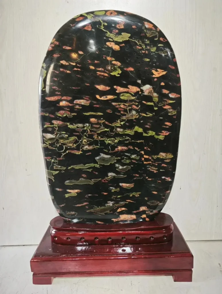 Polished Henan Plum Blossom Jade ornamental carving featuring green, red, and yellow mineral patterns.