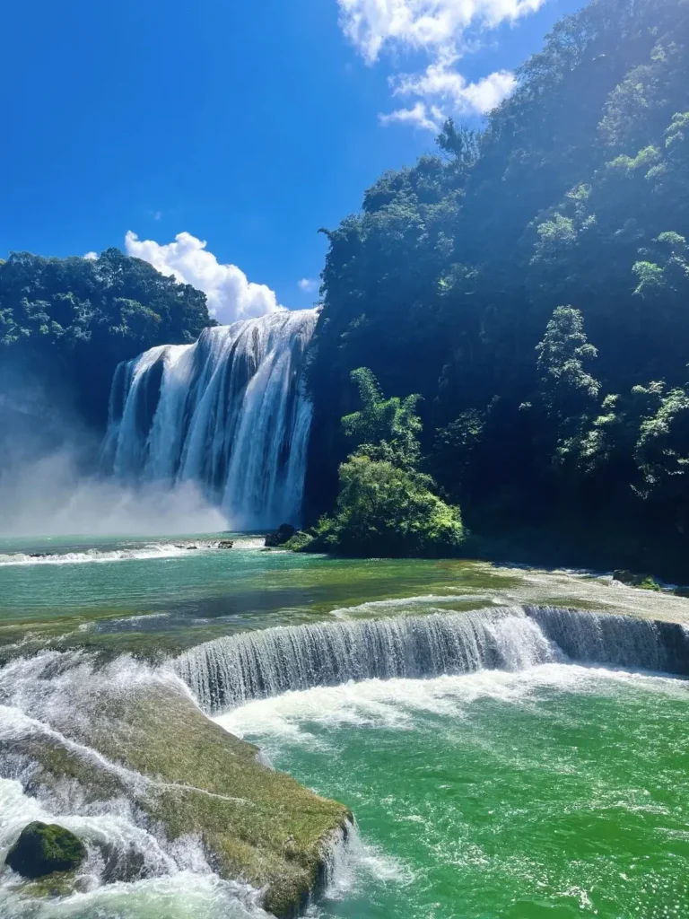 The majestic Huangguoshu Waterfall in Guizhou thunders into a bright turquoise karst river.