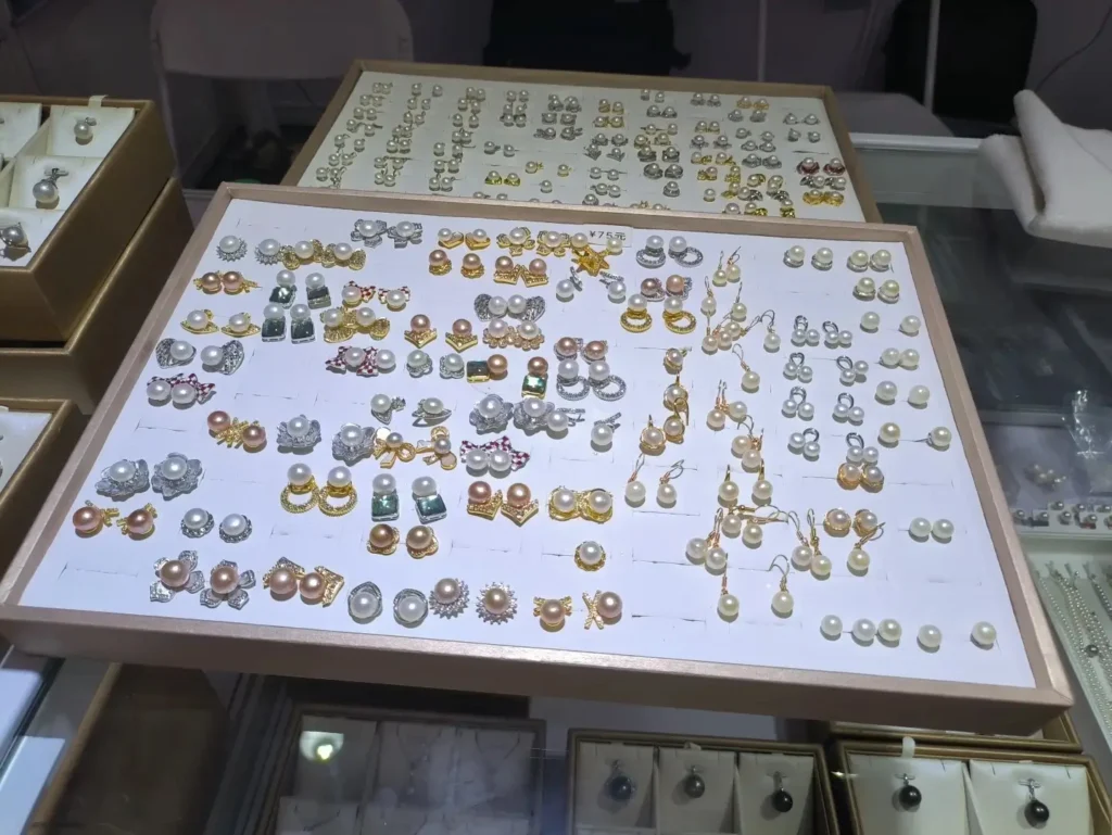 Trays of white, pink, and gold freshwater pearl earrings displayed in a Hunan market case.
