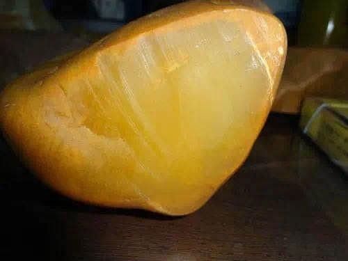 A smooth, honey-yellow Anhui Huoshan quartzite jade rough stone with a waxy, translucent surface. 